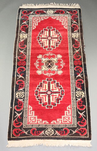 A red and black ground Persian rug with 2 stylised medallions to the centre 176cm x 86cm 