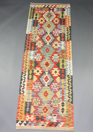 A green, brown and black ground Chobi Kilim runner with diamond design to the centre within a multi row border 252cm x 86cm