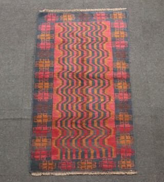 A red, brown and black ground Belouche rug, the central field with wavy decoration 137cm x 78cm 