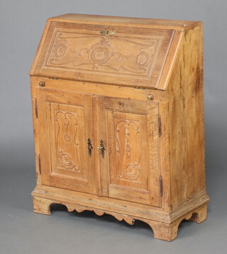 A Continental carved light oak bureau, the fall front revealing a fitted interior with pigeon holes and drawers, base enclosed by panelled doors, raised on bracket feet 103cm h x 84cm w x 35cm d 