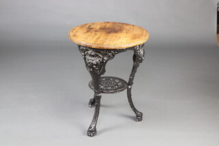 A circular Victorian style pierced cast iron pub table with female head decoration and pine top 70cm h x 55cm diam. 