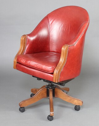 A Victorian style tub back revolving office chair upholstered in red leather, raised on tripod base 98cm h x 60cm x 45cm 