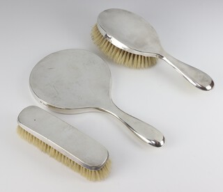 A silver backed hand mirror, clothes brush and hair brush, mixed dates 