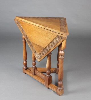 A 17th Century style carved oak drop flap corner Credence table, raised on pillar and tripod supports 66cm h x 65cm w x 54cm d 