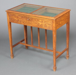 An Edwardian oak rectangular oak display table with fall front, the interior fitted 2 tiers of trays, raised on square tapered supports, spade feet with H framed stretcher 80cm h x 81cm w x 46cm d 