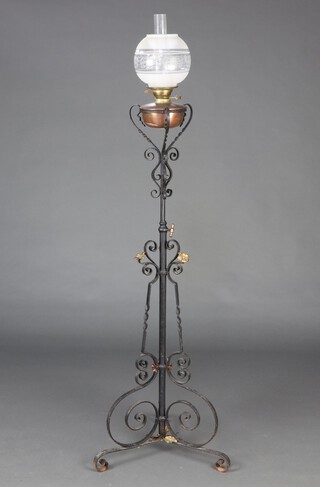 A Victorian wrought iron adjustable standard oil lamp with copper reservoir and etched glass shade, complete with chimney 