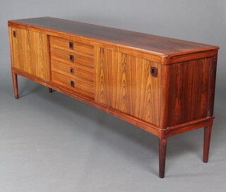 H W Klein for Bramin, a mid Century, 1960's, Danish rosewood sideboard comprising 2 slide panels revealing cupboards and shelves with central column of 4 long drawers, having square recessed handles, raised on tapered supports 80cm h x 225cm w x 45cm.  Supplied with a Cites Article 10 certificate, No. 24GBA108HAIQE