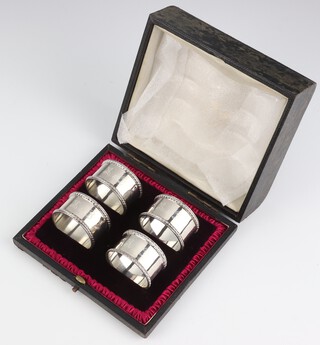 A set of 4 Edwardian silver napkin rings, monogrammed, London 1903, 126 grams, cased  