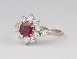 A white metal 18ct ruby and diamond cluster ring, the circular centre stone approx 1.2ct, surrounded by 10 brilliant cut diamonds, each approx 0.10ct, the shoulders each set with 1 diamond approx 0.05ct, size V, 5.6 grams 