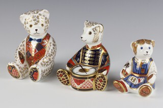 A Royal Crown Derby  paperweight in the form of a seated bear with gold stopper LXI 12cm, ditto bear drummer with gold stopper LXII and a school girl teddy bear with gold stopper MMIII 10cm 