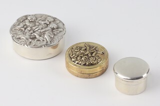 An Edwardian style circular silver repousse pill box decorated with cherubs London 1978 4cm and 2 others, 62 grams 