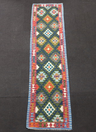 A blue, green and black ground Kilim runner with all over geometric design 305cm x 81cm 