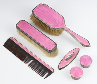 A silver and pink guilloche enamel dressing table set London 1932, comprising clothes brush, hair brush, comb mount, buffer mount, 2 circular boxes, all bruised 