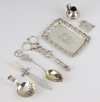 An Edwardian Reynolds angels silver pin tray, a pair of sugar nips, stamp envelope, caddy spoon, book mark, spoon and jug base, 102 grams 