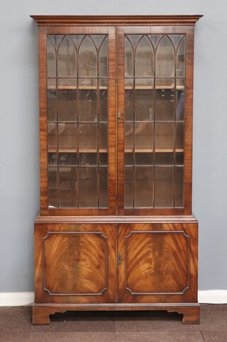 A Georgian style mahogany bookcase on cabinet with moulded cornice, fitted shelves enclosed by astragal glazed panelled doors, the base enclosed by panelled doors, raised on bracket feet 185cm h x 101cm w x 35cm d 