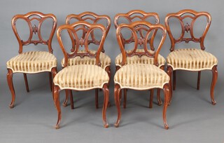 A set of 6 Victorian carved walnut "Admiralty" tulip backed chairs with over stuffed seats, raised on carved cabriole supports