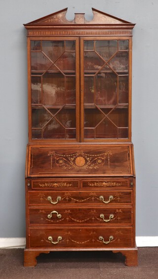 An Edwardian Sheraton style inlaid mahogany bureau bookcase with broken pediment, fitted shelves enclosed by astragal glazed panelled doors, the base with fall front revealing a well fitted interior above 2 short and 3 long drawers, raised on bracket feet 198cm h x 83cm w x 42cm d 