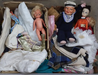 A collection of dolls and dolls clothes contained in a plastic box