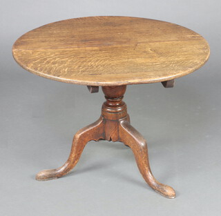 An 18th Century circular oak snap top tea table raised on a turned column and tripod base 55cm h x 77cm diam. (cut down, top warped and split, sun bleached, water marks)