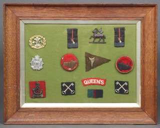 A collection of cap and divisional badges including the Border Regiment, British 2nd Division, contained in an oak frame 24cm x 34cm