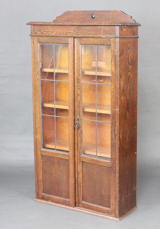 A 1930's oak display cabinet with raised back fitted shelves enclosed by lead glazed panelled doors 140cm h x 76cm w x 27cm d (contact marks in places)