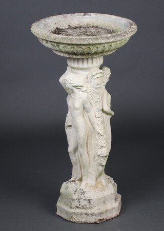 A concrete birdbath supported by three ladies