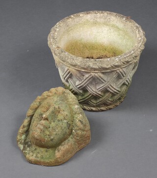 A circular well weathered basketwork planter and a concrete wall mask planter