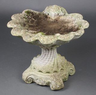 A concrete scalloped shaped bird bath in two sections