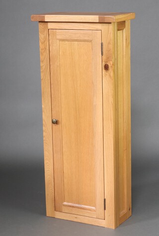 A light oak cabinet with shelved interior enclosed by panelled door 114cm h x50cm w x 25cm d