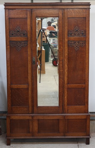 A 1930's light oak wardrobe with moulded cornice enclosed by a mirrored panelled door 196cm h x 115cm w x 46cm d 