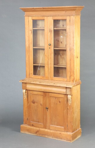 A 19th Century pine bookcase on cabinet with moulded cornice, fitted shelves enclosed by glazed panelled doors, the base fitted a drawer above a panelled door, raised on a platform base 194cm h x 87cm w x 36cm d (water and contact marks in places) 