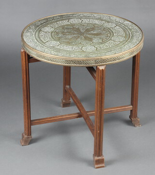 A circular Eastern embossed brass table top, raised on an oak folding stand 57cm h x 60cm diam. 