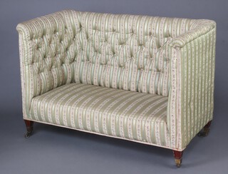 An Edwardian high backed sofa upholstered in Regency striped buttoned back material, raised on square supports, brass caps and casters 97cm h x 139cm w x 71cm d (seat 100cm x 45cm) 