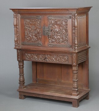 A Victorian Continental carved oak cabinet with carved columns to the sides, the upper section fitted a cupboard enclosed by heavily carved panelled doors, the base fitted 1 long drawer above an undertier  147cm h x 118cm w x 54cm d 