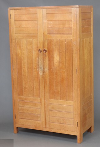 A Heals style light oak wardrobe, fitted shelves and hanging space, enclosed by a panelled door 180cm h x 105cm w x 52cm d, the back marked 303 and 12 within a circle  