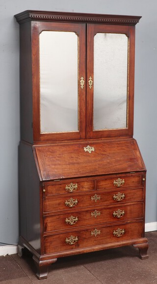 A Georgian mahogany cabinet on bureau with moulded and dentil cornice, the associated top fitted shelves, pigeon holes enclosed by a pair of mirror panelled doors with gilt chamfering to the edge, the fall front revealing a well fitted interior above 2 short and 3 long drawers, raised on ogee bracket feet 214cm h x 99cm w x 53cm d 