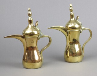 A pair of Arabic Dallah brass coffee pots with heart shaped mark 28cm h 