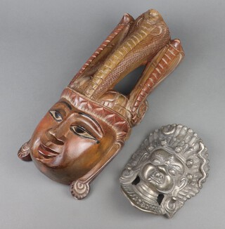 An Eastern cast metal wall mask 20cm x 14cm and a carved wooden ditto 43cm x 18cm 