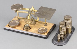 A pair of Edwardian brass postage scales together with a collection of 9 brass bell weights, 5 grams to 500 grams, raised on an iron stand 