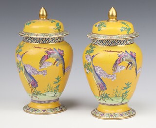 A pair of 1930's yellow ground baluster vases and covers decorated with exotic birds 23cm 