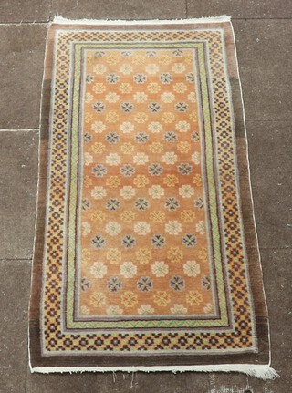 A Chinese brown and green ground rug with all over floral design to the centre within a multi row border 139cm x 67cm 