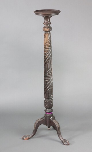 A carved mahogany bed post torchere with saucer top, raised on tripod supports with egg and paw feet 136cm h x 26cm d 