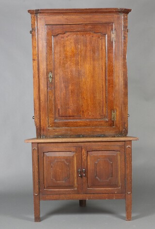 An 18th Century oak hanging corner cabinet with moulded cornice, fitted shelves enclosed by inlaid panelled door (108cm h x 86cm w x 43cm d), raised on a later associated base 181cm h (together) x 96cm w x 65cm d