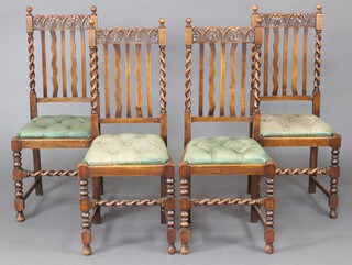 A set of 4 1930's carved oak framed stick and rail back dining chairs with spiral turned columns to the side, drop in seats upholstered in buttoned leather 109cm h x 46cm w x 41cm d 