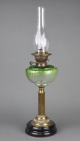 A Victorian oil lamp with green glass reservoir, raised on a gilt metal reeded and ceramic socle base 46cm h x 12cm, complete with clear glass chimney 