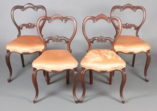 A set of 4 Victorian rosewood ballon back dining chairs with carved mid rails, over stuffed seats of serpentine outline, raised on cabriole supports 