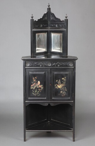 A Victorian aesthetic movement ebonised corner cabinet, the raised upper section fitted a shelf above niche with rectangular bevelled plate panels, base enclosed by painted panelled doors, decorated birds above recess 160cm h x 56cm w x 63cm d  