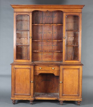 A Victorian oak dog kennel dresser, the raised back with moulded cornice fitted 3 shelves flanked by cupboards enclosed by arched panelled doors, the base fitted a drawer above recess flanked by cupboards, raised on bun feet 210cm h x 151cm w x 43cm d  