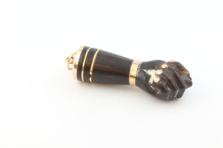 A yellow gold testing as 18ct mounted carved ebony pendant in the form of a clenched fist enclosing the thumb 30mm