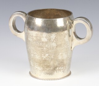 An Edwardian Arts and Crafts style hammer pattern 2 handled cup London 1902, with beaded foot, maker Goldsmiths and Silversmiths Company, 13cm, 498 grams  